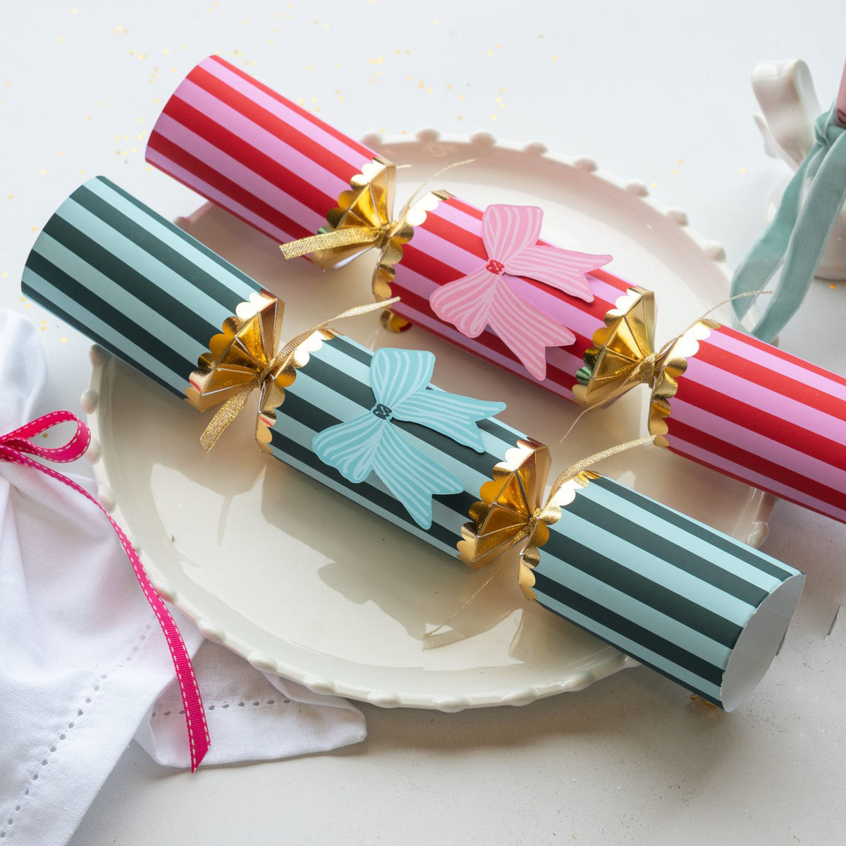 Close up of red and teal striped crackers with gold scalloped detailing and bow accents.