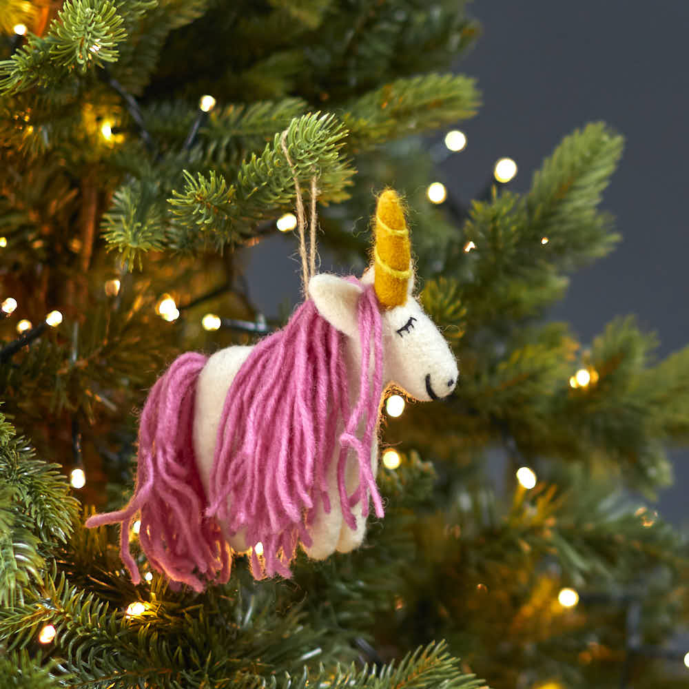 Mystic unicorn felt decoration hanging on a lit Christmas tree branch with soft festive lighting