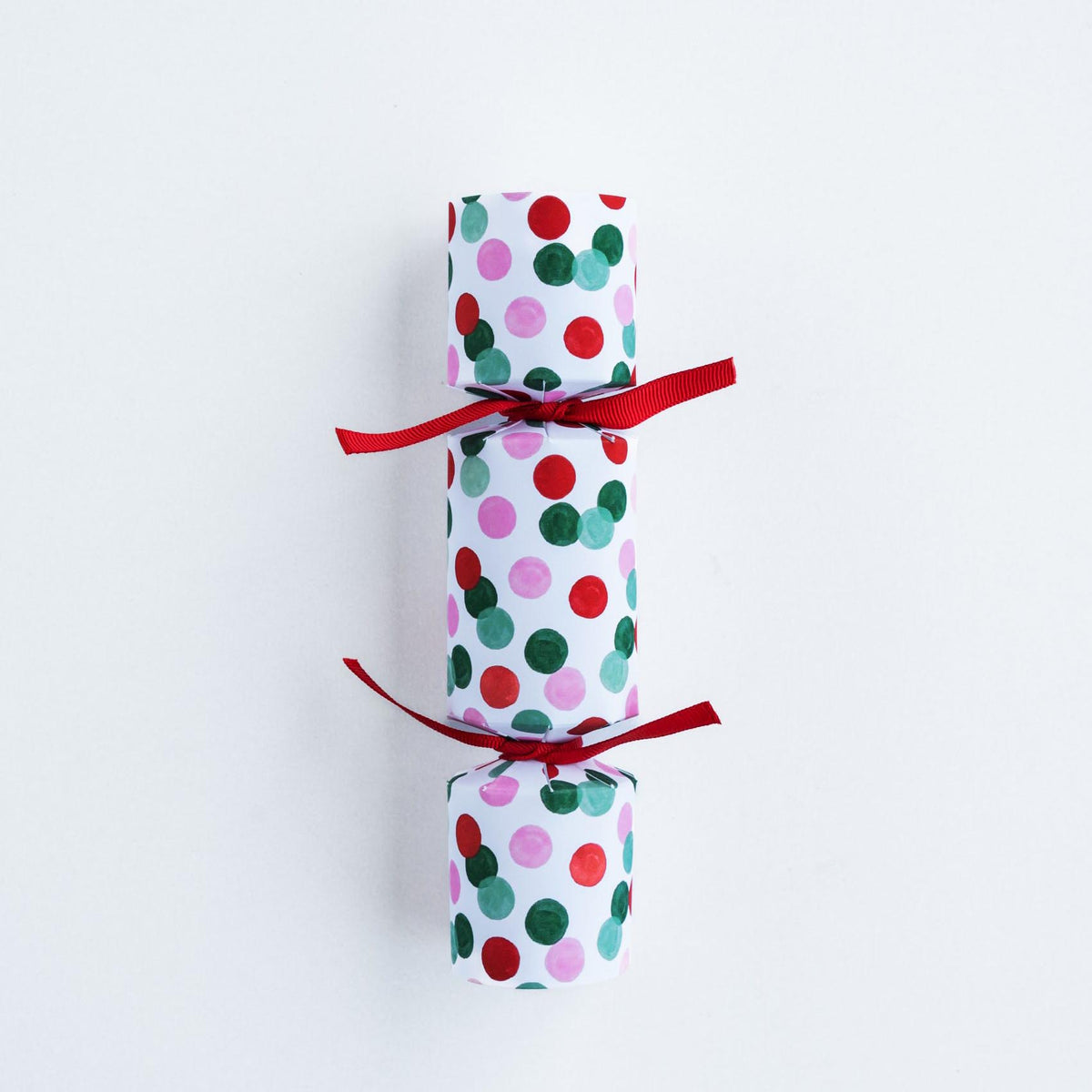 Single petite Christmas cracker showing the red, green, and pink dot pattern against a plain white background.
