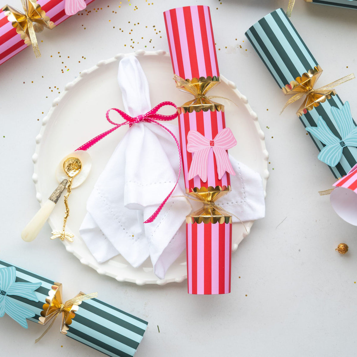 A Christmas cracker styled on a white plate with a linen napkin and salt spoon.
