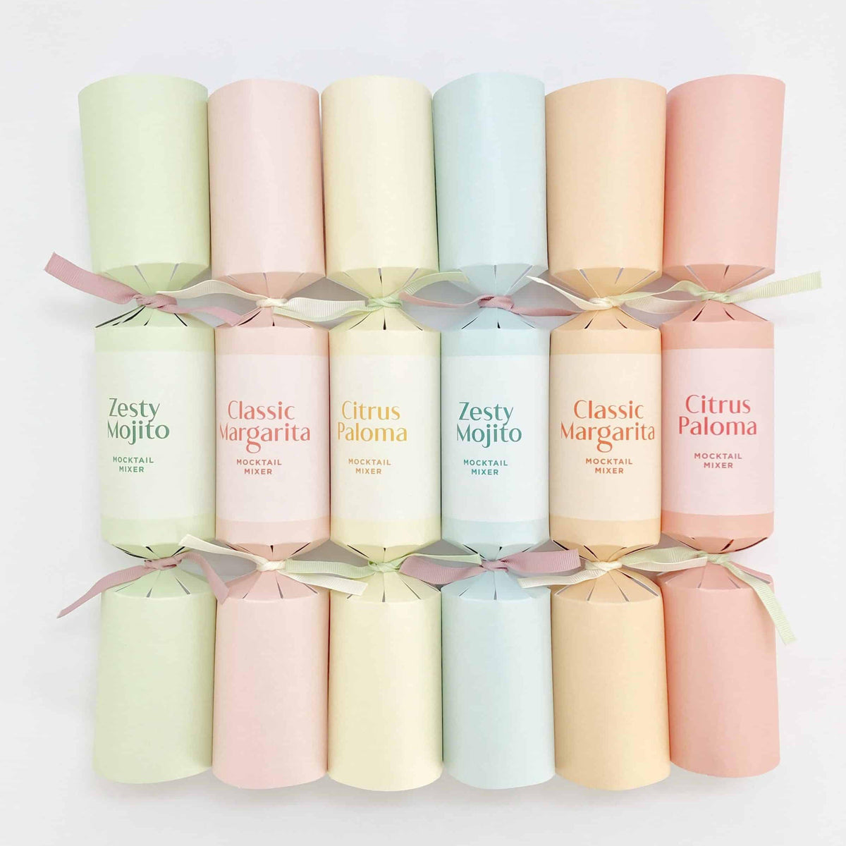 Six 14-inch Christmas crackers laid flat showing the full pastel colour palette and ribbon ties.