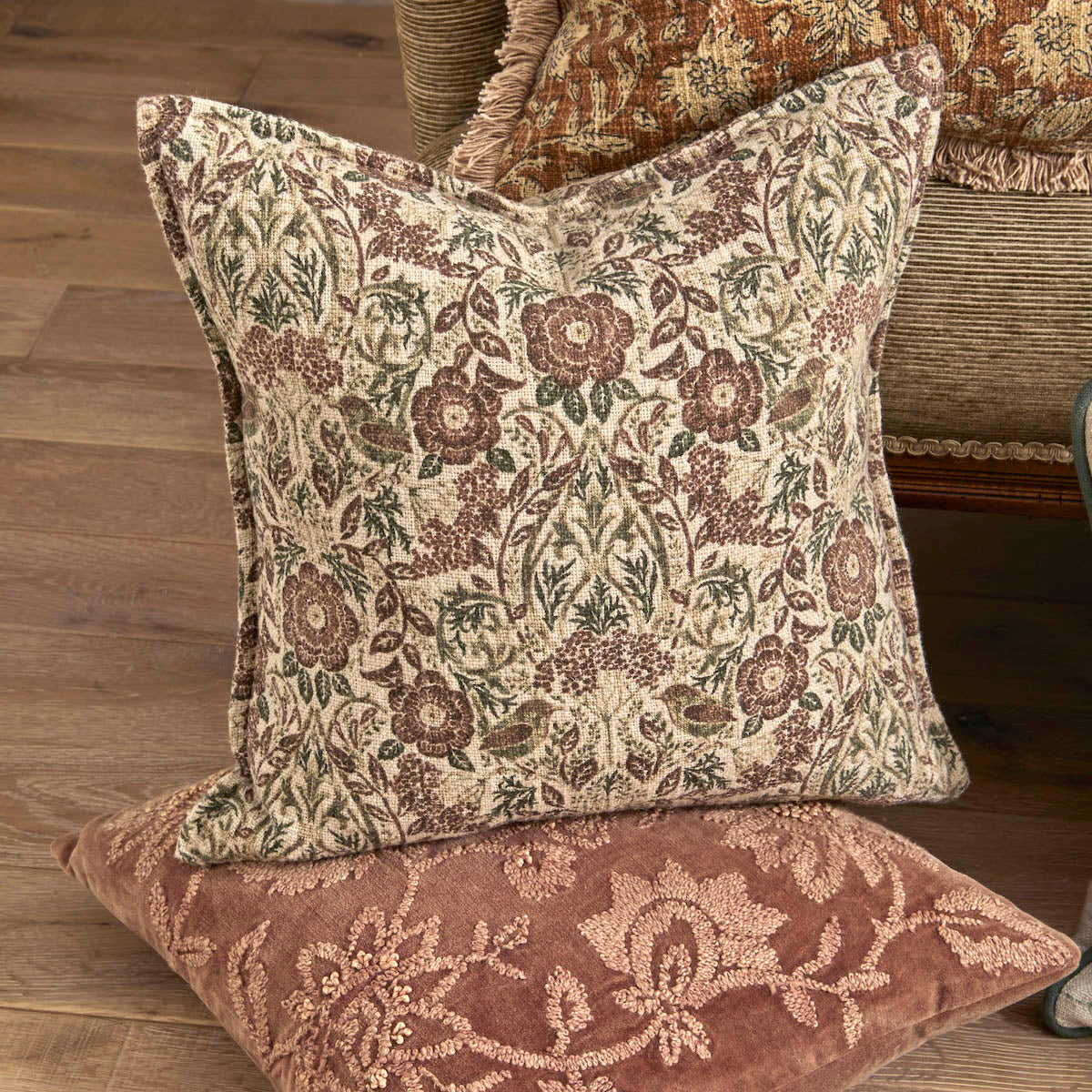 Jenny Wren botanical print cushion styled in a living room setting stacked with other neutral toned cushions.