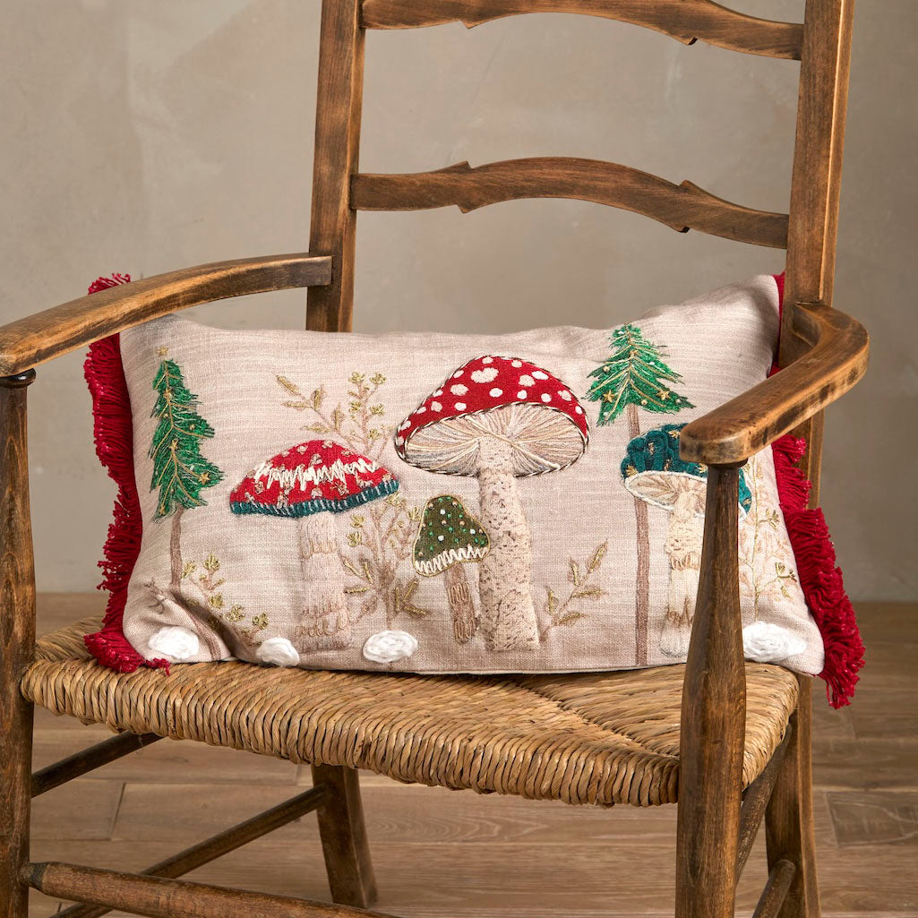 Embroidered toadstool cushion styled on a rustic wooden armchair with a rush seat.