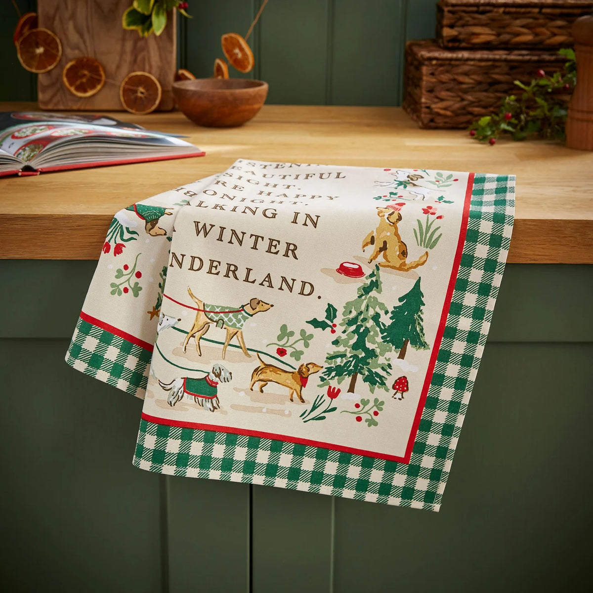 Festive cotton tea towel styled on a kitchen worktop, showing the dog and pine tree watercolour design.
