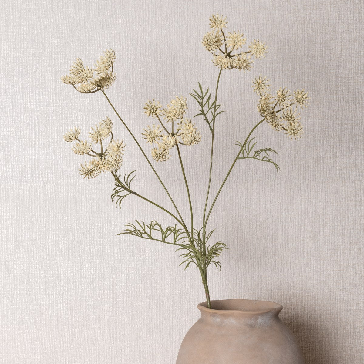 Lifelike Queen Anne's Lace artificial stem styled in a rustic ceramic vase against a textured wall