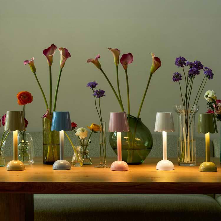 A collection of scalloped rechargeable lamps in various pastel and earth tones displayed on a dining table.