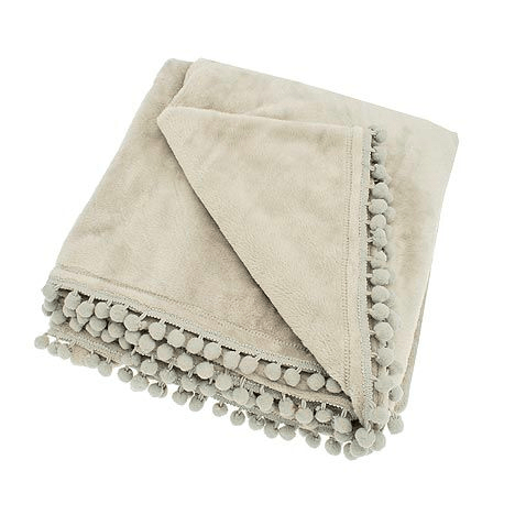Folded linen-coloured fleece throw with decorative pom-pom braid edging.