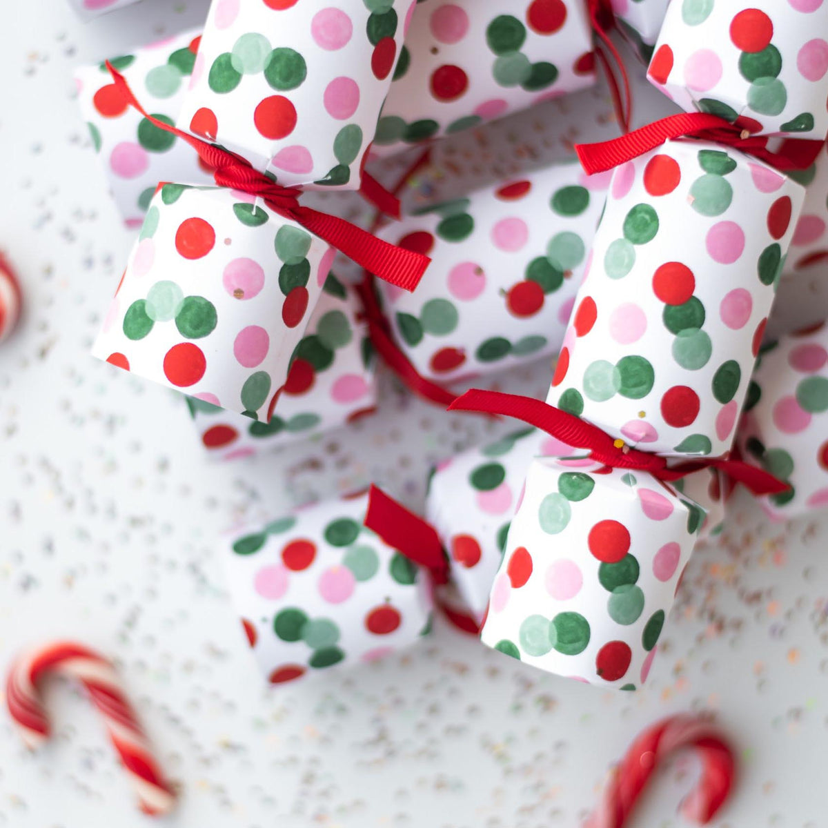 A pile of petite confetti dot crackers scattered on a white surface with red candy canes.