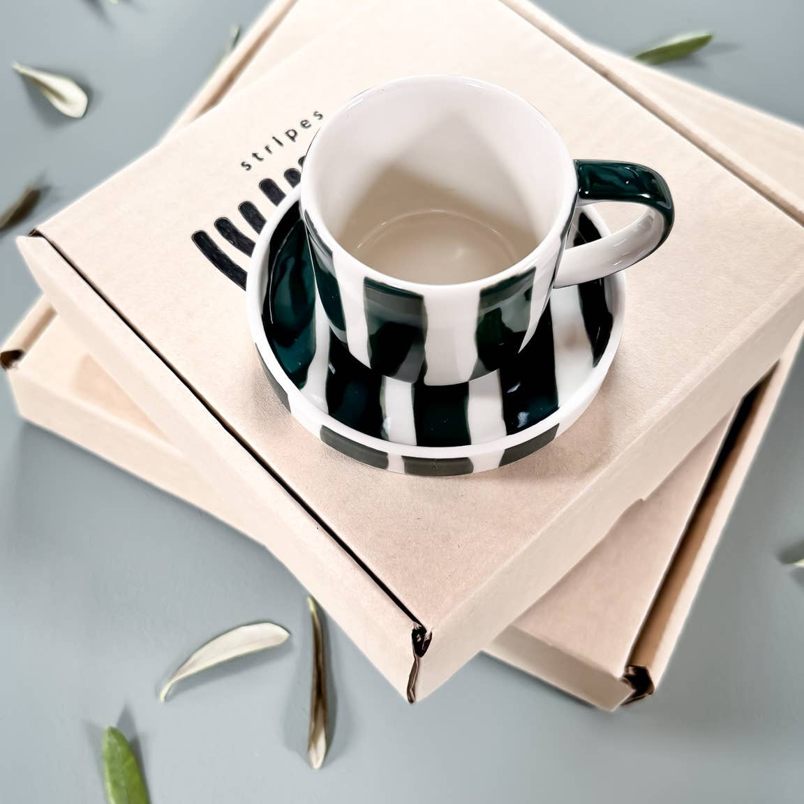 Green striped espresso cup and saucer set presented on a simple cardboard gift box