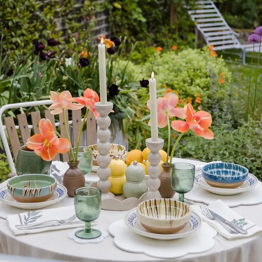 A pair of cappuccino bobbin candlesticks styled on an outdoor dining table with colourful tableware and flowers