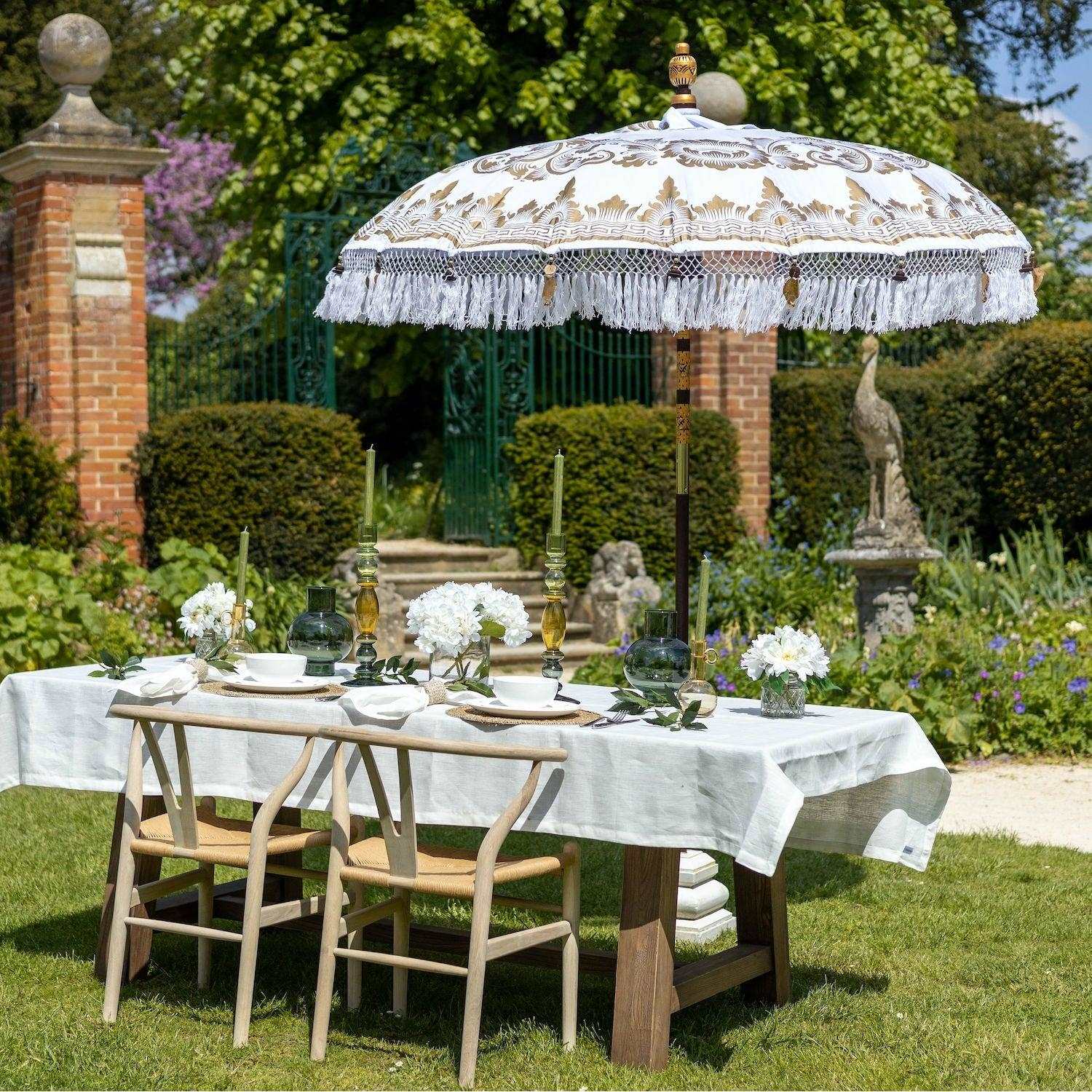 The Bali sun parasol providing shade over a dressed outdoor dining table in a sunlit English country garden.