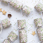 Close-up of kraft paper crackers with mistletoe print and white ribbon ties