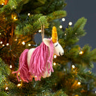 Mystic unicorn felt decoration hanging on a lit Christmas tree branch with soft festive lighting