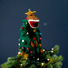 Handmade felt Tree-Rex topper styled on top of a Christmas tree with festive lights