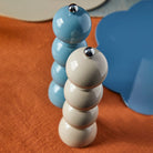 Close-up of two lacquered bobbin grinders in cappuccino and chambray blue on an orange textured cloth