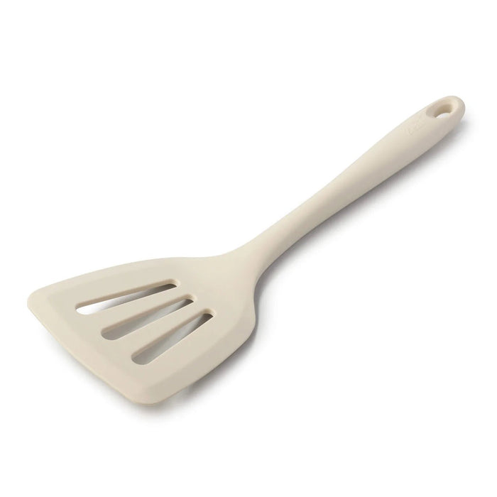 Cream silicone slotted turner with a flexible head and hanging hole in the handle.
