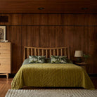 Lifestyle shot of the Larsen oak bed in a dimly lit room with matching chest of drawers
