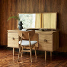 Larsen oak dressing table styled in a bedroom with a matching oak chair and decorative accessories.