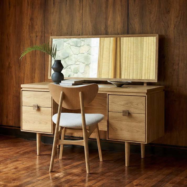 Larsen oak dressing table styled in a bedroom with a matching oak chair and decorative accessories.