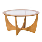 G Plan Larsen round oak coffee table with sculptural base and glass top on a white background