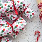 Stack of colourful dotted Christmas crackers with red ribbons and festive styling.
