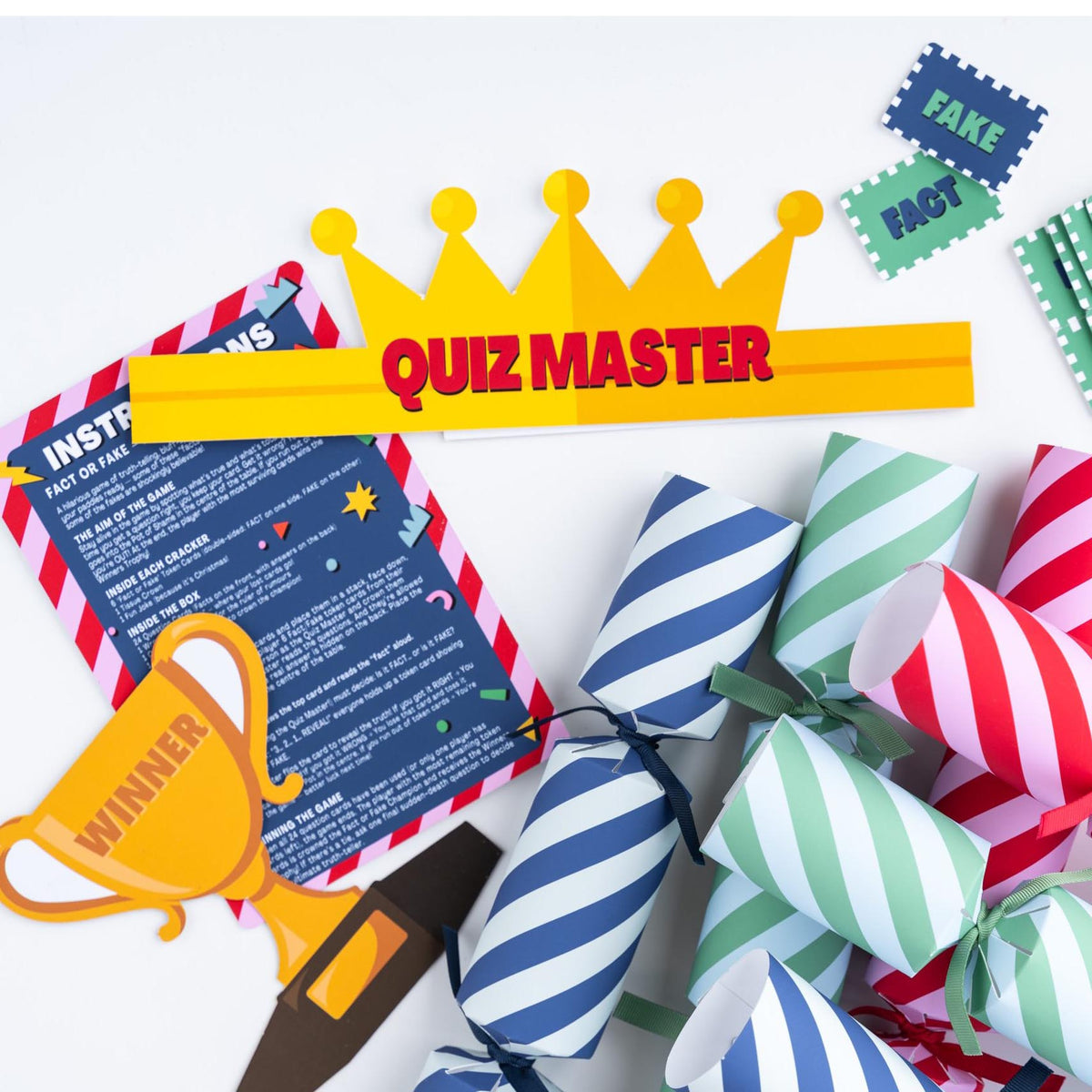 Festive game components including quiz master crown, winner trophy, and striped Christmas crackers.