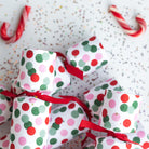 Close-up of confetti dot Christmas crackers on a festive white background with glitter and candy canes.