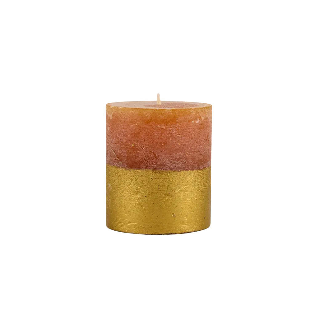 Textured orange pillar candle with a metallic gold-dipped base on a plain white background
