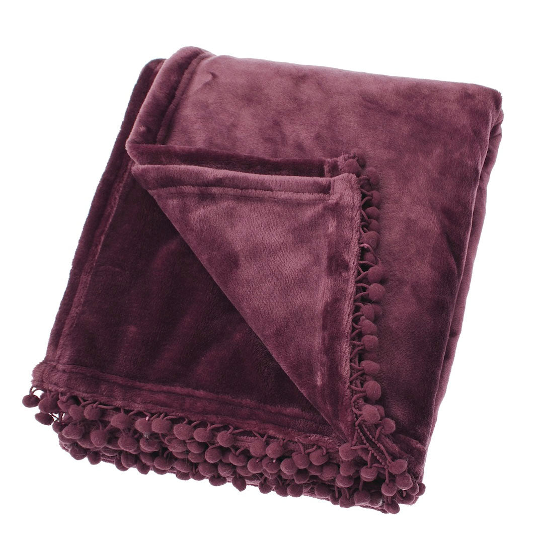 Folded mulberry fleece throw with a decorative pom-pom braid edge on a white background.