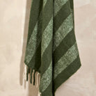 Close-up of the wide stripe pattern and fringed edge of the fern green wool blend throw