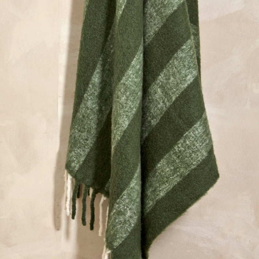 Close-up of the wide stripe pattern and fringed edge of the fern green wool blend throw