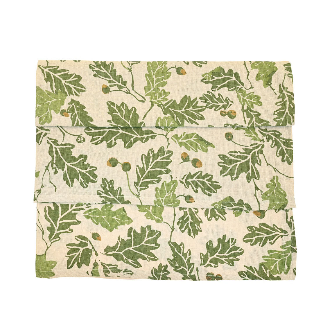 Folded linen table runner with a green oak leaf and acorn print on a cream background.