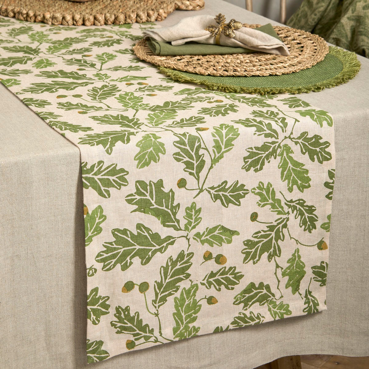 Acorn and oak leaf print linen table runner styled on a neutral tablecloth with rustic place settings.