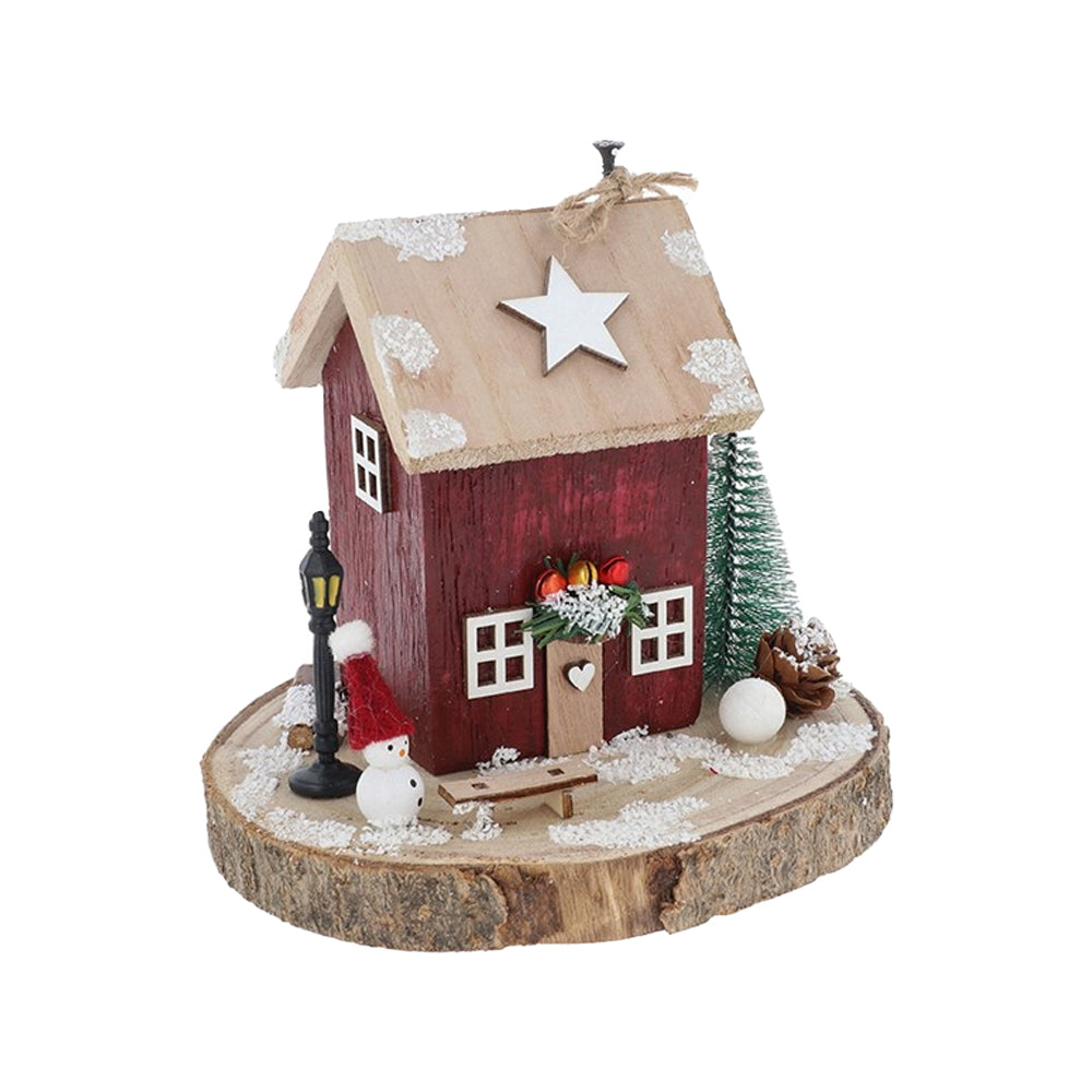 Red wooden folk art Christmas cottage on a log base with a miniature snowman and lamp post