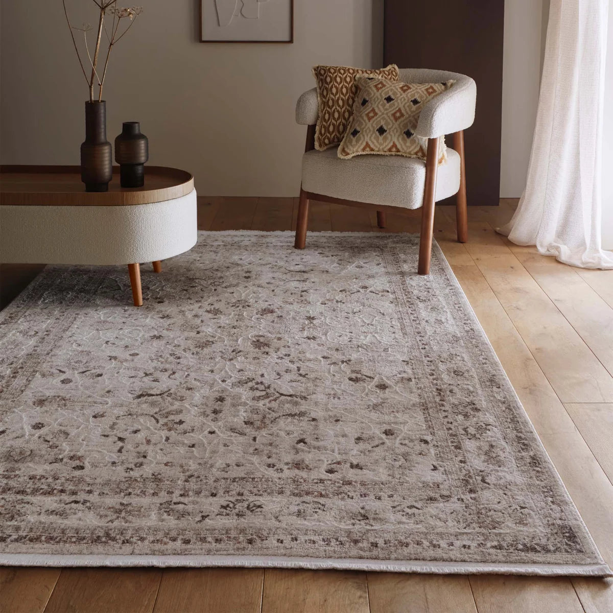 Lifestyle view of the Aurelia Cream rug in a living space with an armchair and side table.