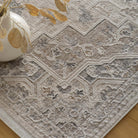 Top-down close-up of the cream rug styled with a white vase and dried foliage.