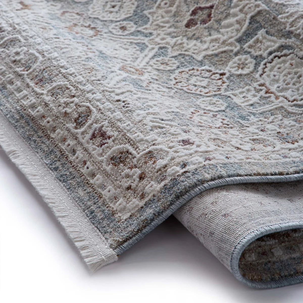 The Celeste Sea Green rug partially rolled to show the backing and the soft, short fringe at the edge.