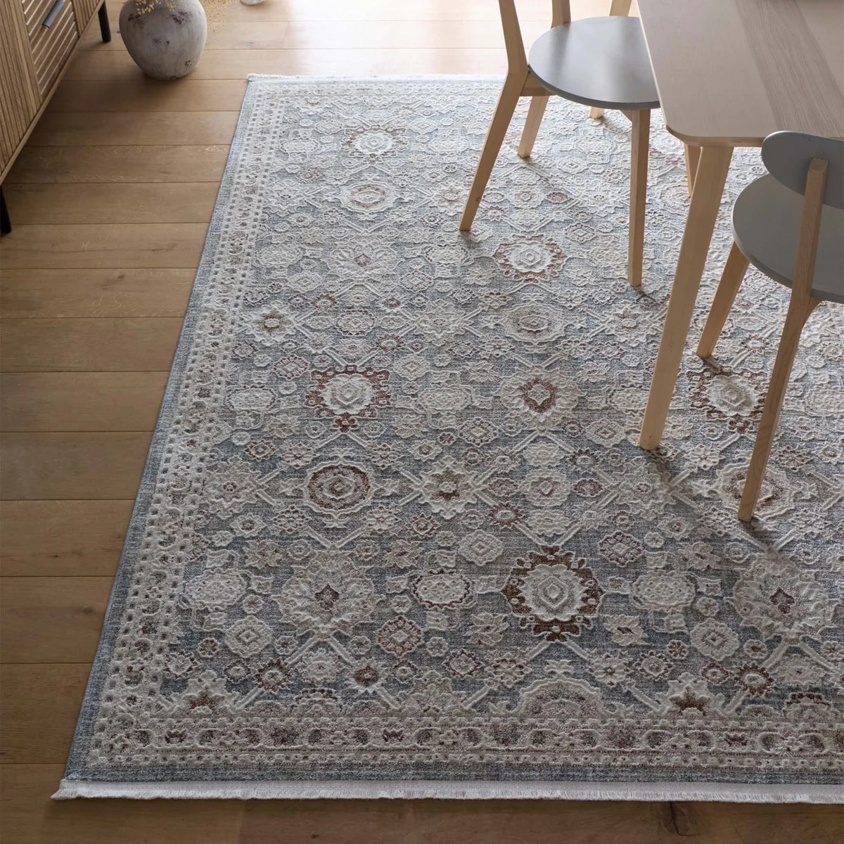 Celeste Sea Green rug styled in a dining room under a wooden table and chairs.