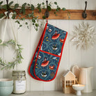 Festive double oven glove hanging from a wooden peg rail in a styled kitchen setting.