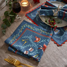 Festive table setting with 12 Days of Christmas cotton napkins paired with matching placemats and greenery.