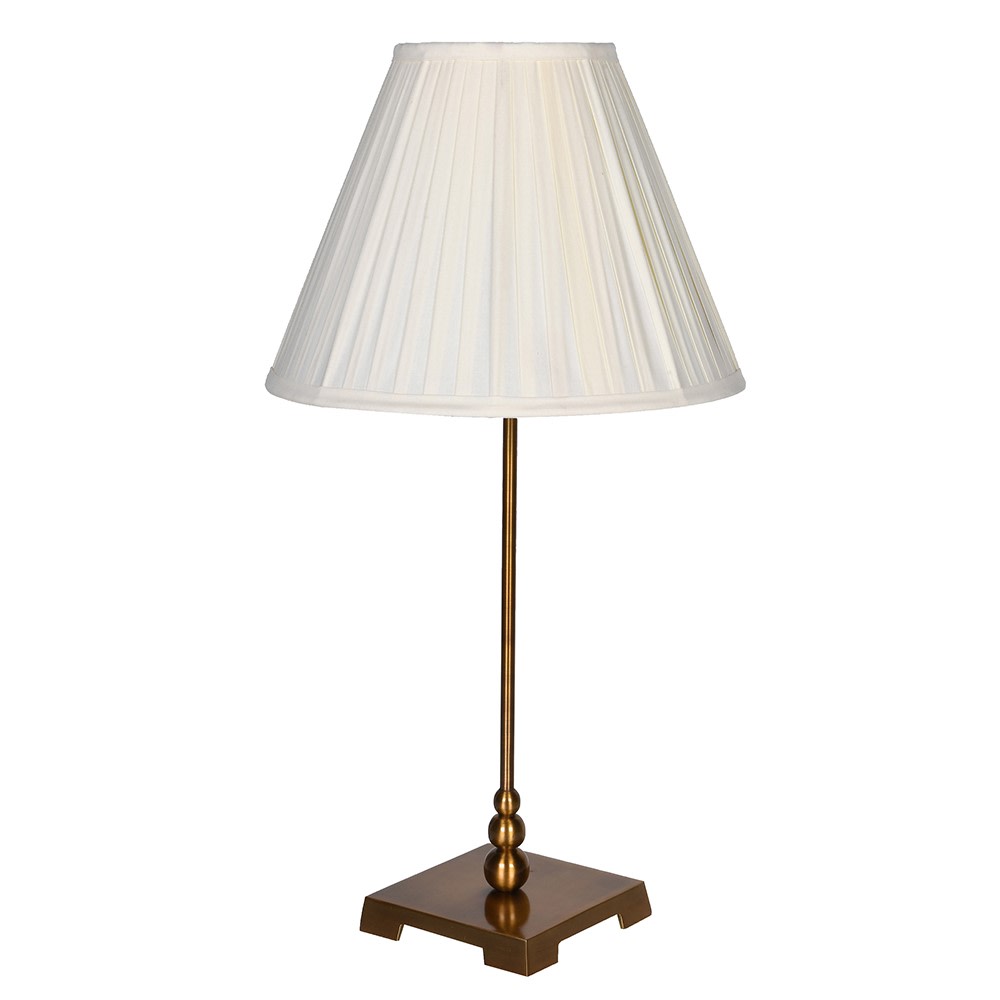 Slim table lamp with antique brass stem and square base, topped with a cream pleated shade against a white background.