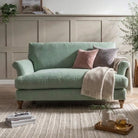Lacey snuggler sofa in sage green fabric styled in a neutral living room with a cream rug
