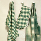 Foliage green gingham tea towel styled hanging alongside matching oven gloves and apron