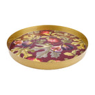 Round gold metal tray showing the raised rim and botanical fig and pomegranate design against a burgundy background.