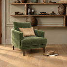 Green velvet Florence armchair styled in a living room with wooden shelving and decorative objects
