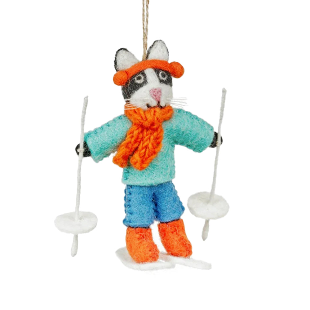 Handmade felt cat decoration wearing a teal jumper and orange scarf holding white ski poles on a plain background