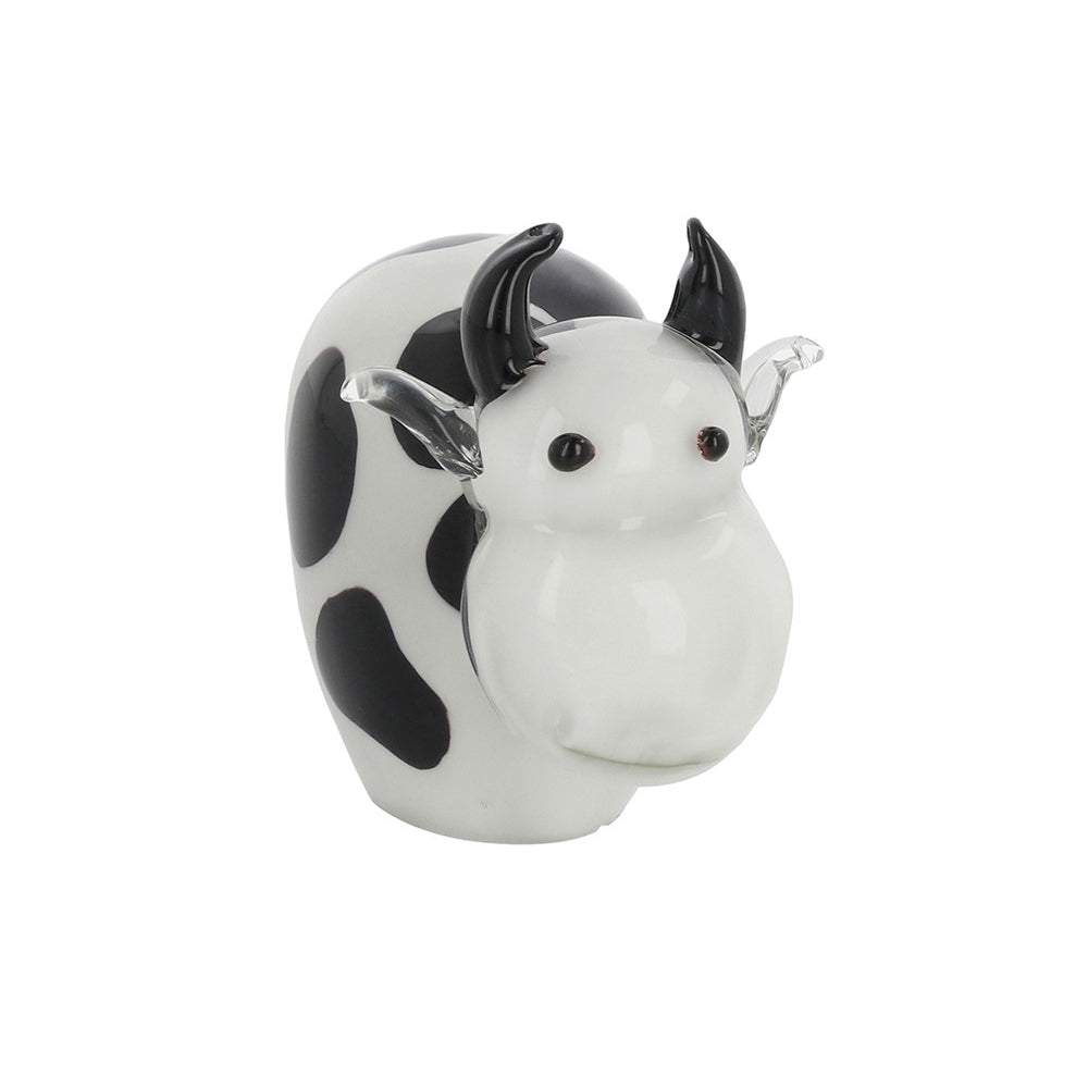 Handmade glass cow ornament with black spots and small black horns on a white background