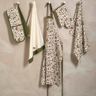 Into the Woods kitchenware collection including tea towels, apron, and oven gloves hanging on pegs.