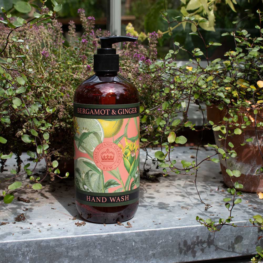 The botanical hand wash bottle styled outdoors on a lead surface surrounded by lush garden greenery.