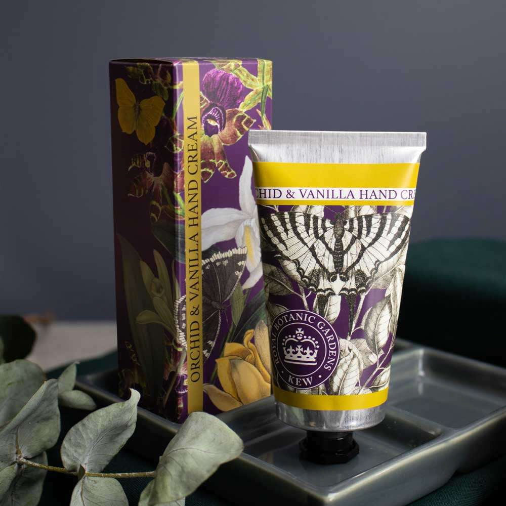 Close-up of the Kew Gardens hand cream tube and gift box styled on a tray with eucalyptus leaves